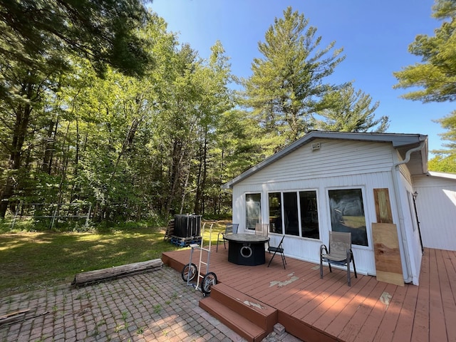 wooden deck with an outdoor fire pit, a patio area, and a lawn