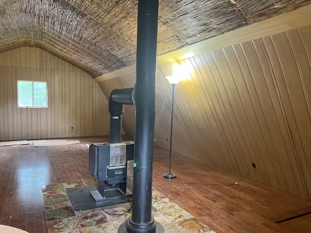 bonus room with a wood stove, wooden walls, vaulted ceiling, and wood finished floors