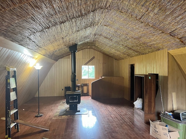 bonus room featuring lofted ceiling, hardwood / wood-style flooring, a wood stove, and wooden walls