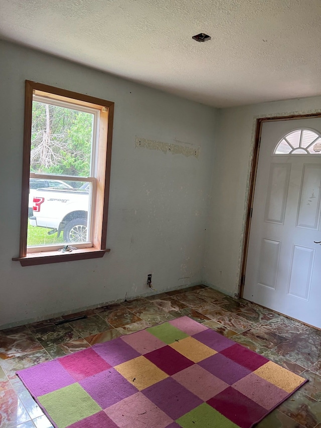 entryway with a textured ceiling and tile patterned floors