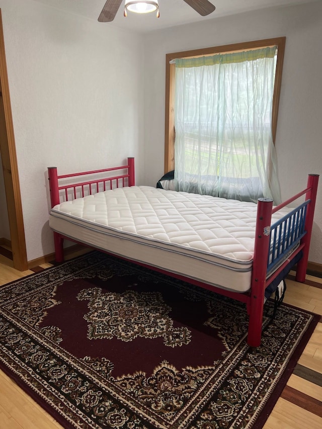 bedroom with baseboards, a ceiling fan, and wood finished floors