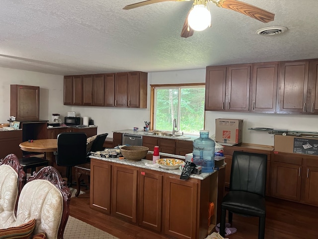 kitchen with stainless steel dishwasher, dark wood-style flooring, a kitchen island, a textured ceiling, and a sink