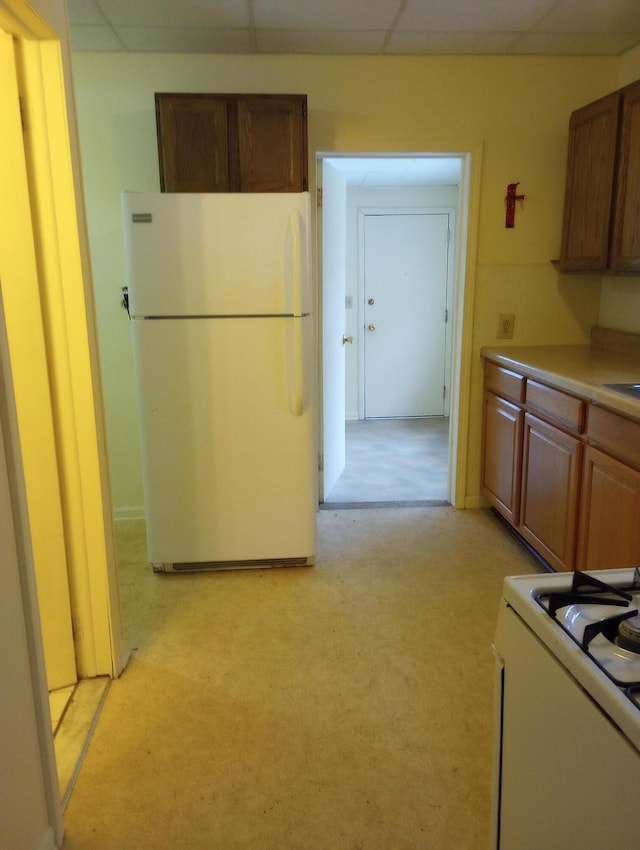 kitchen featuring light countertops, white appliances, and a drop ceiling