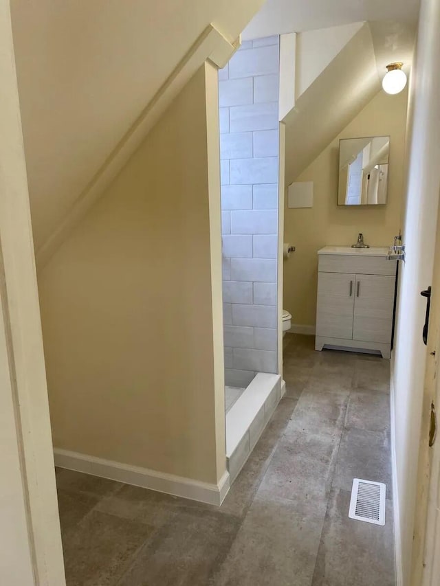 bathroom featuring lofted ceiling, visible vents, toilet, vanity, and tiled shower