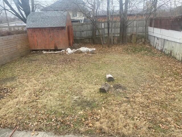 view of yard featuring a storage shed, a fenced backyard, and an outdoor structure