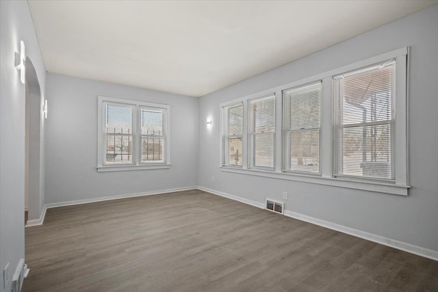 unfurnished room with dark wood finished floors, visible vents, and baseboards