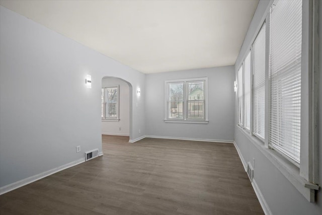 spare room with plenty of natural light, visible vents, and arched walkways