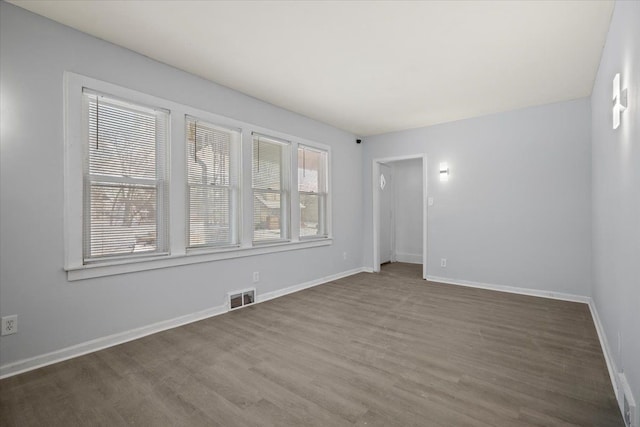 empty room featuring visible vents, baseboards, and wood finished floors