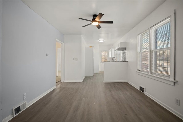 unfurnished living room with dark wood-style floors, baseboards, and visible vents