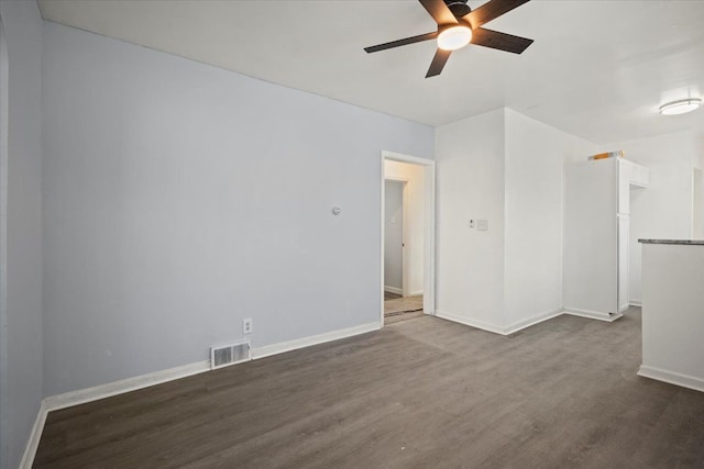 unfurnished room featuring visible vents, dark wood finished floors, baseboards, and ceiling fan