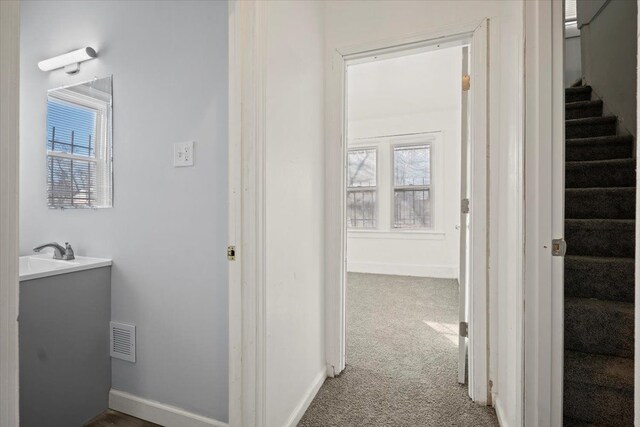 hallway featuring carpet floors, visible vents, stairway, and baseboards