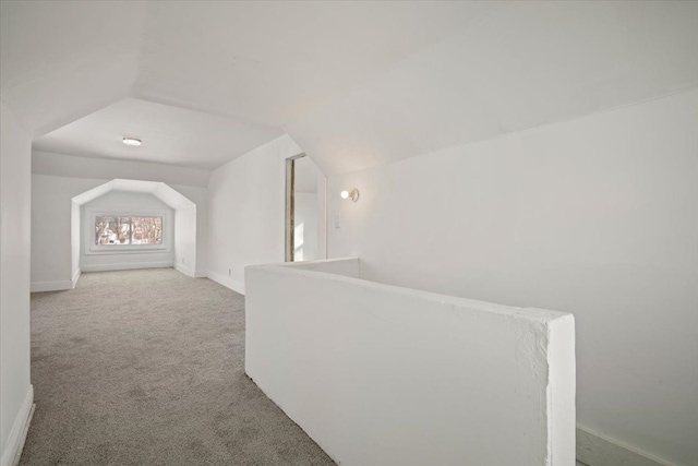 hallway featuring vaulted ceiling, carpet, and baseboards