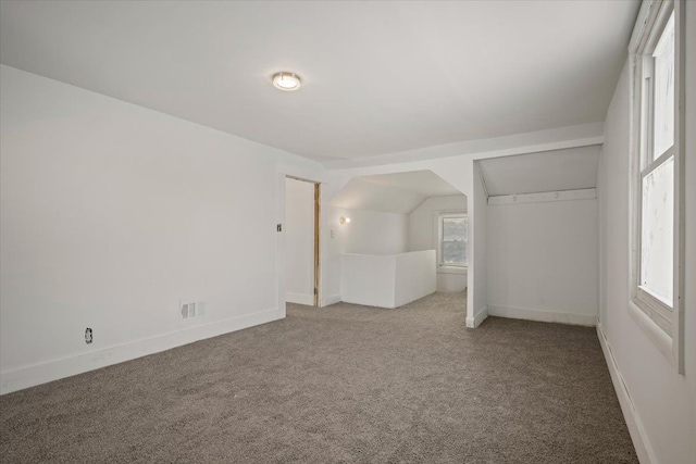 unfurnished bedroom with carpet floors, lofted ceiling, visible vents, and baseboards