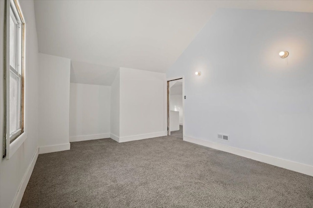 interior space with baseboards, vaulted ceiling, and carpet flooring