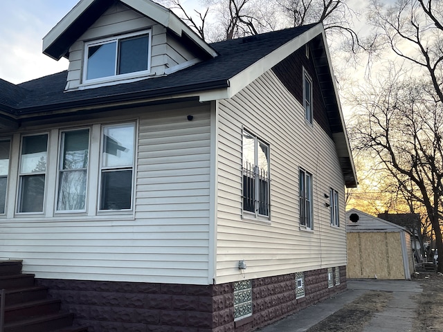 view of property exterior featuring roof with shingles and an outdoor structure