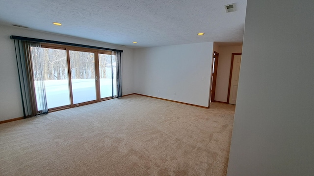 spare room with light carpet, a textured ceiling, visible vents, and baseboards