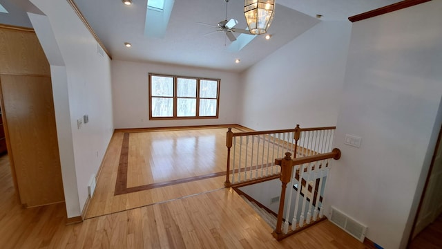 interior space with light wood-style flooring, a skylight, visible vents, and a ceiling fan