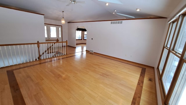 spare room with arched walkways, lofted ceiling with skylight, and visible vents