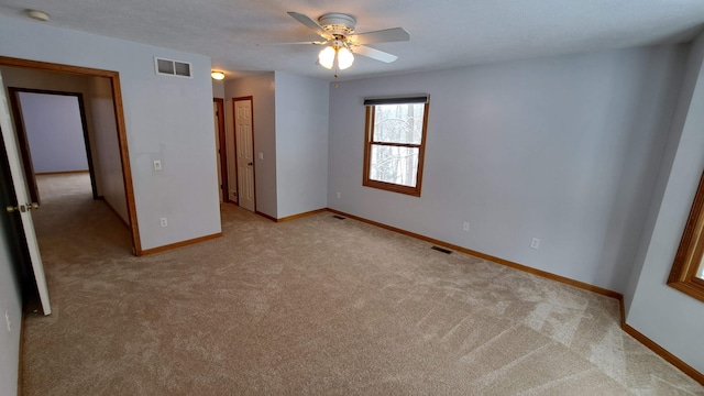 unfurnished bedroom featuring ceiling fan, light colored carpet, visible vents, and baseboards