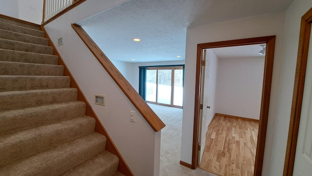 stairway featuring recessed lighting, visible vents, a textured ceiling, wood finished floors, and baseboards