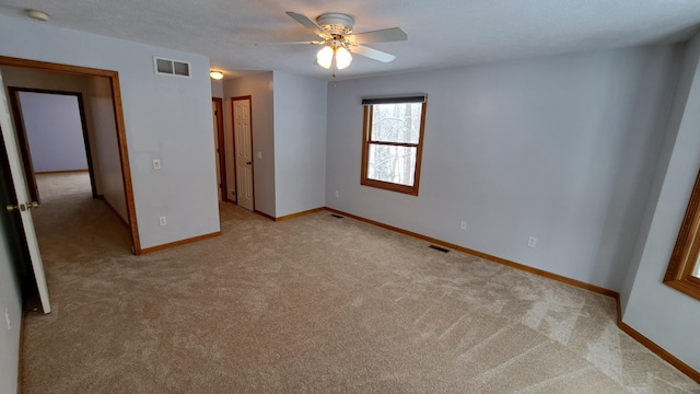 unfurnished bedroom featuring baseboards, visible vents, ceiling fan, and light colored carpet