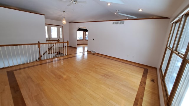 unfurnished room with arched walkways, lofted ceiling with skylight, and visible vents