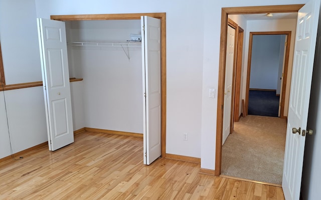 unfurnished bedroom with a closet, light wood-type flooring, and baseboards