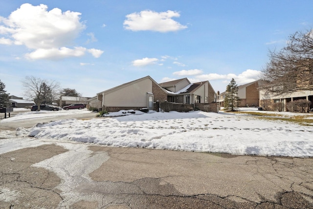 snow covered property featuring brick siding