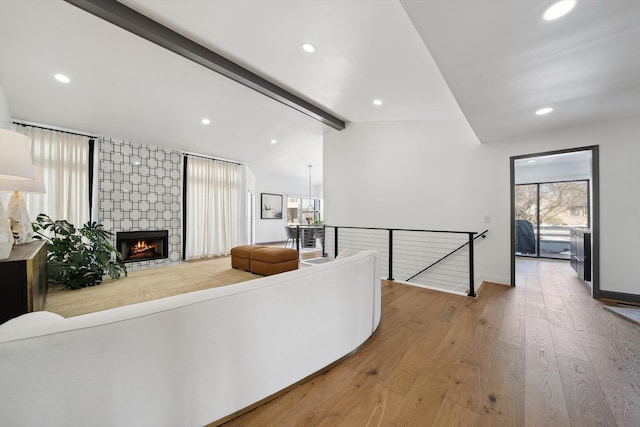 living area with lofted ceiling with beams, hardwood / wood-style floors, a fireplace, and recessed lighting