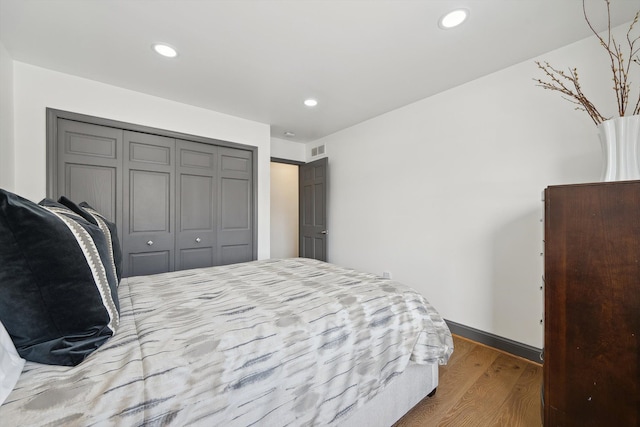 bedroom with a closet, visible vents, wood finished floors, and recessed lighting