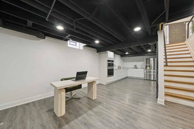 office featuring a sink, wood finished floors, and baseboards