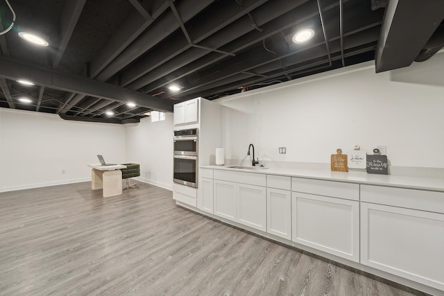 interior space featuring light wood-style flooring, baseboards, and a sink