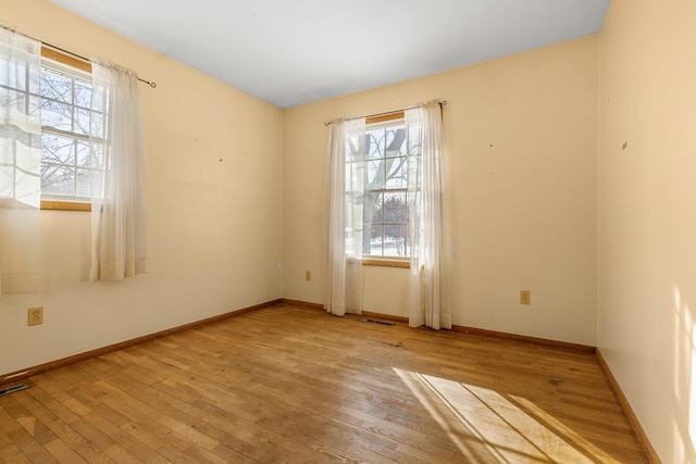 unfurnished room featuring light wood-type flooring, visible vents, and baseboards