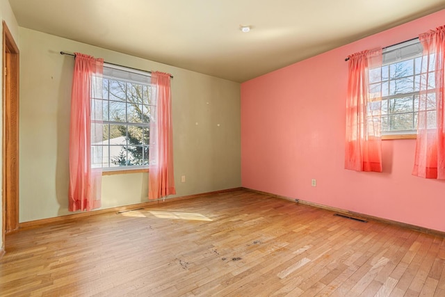 spare room with visible vents, light wood-style flooring, and baseboards