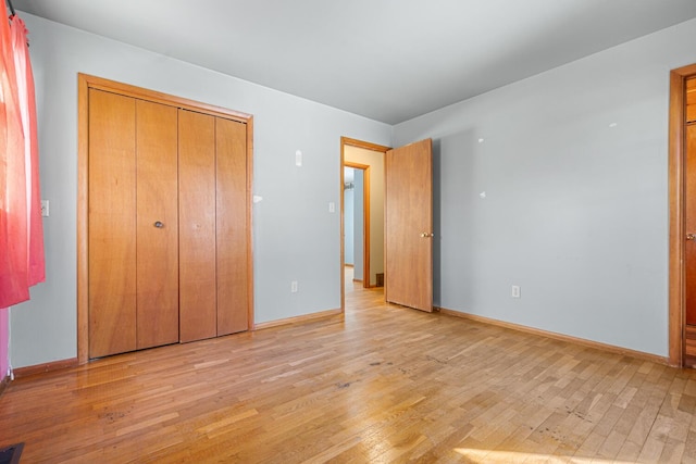 unfurnished bedroom with light wood finished floors, baseboards, and a closet