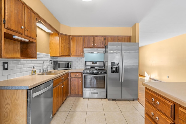 kitchen with appliances with stainless steel finishes, light countertops, brown cabinetry, and under cabinet range hood