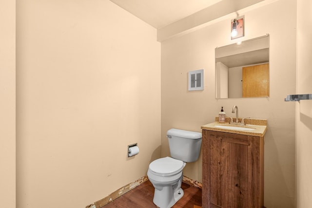 half bath featuring baseboards, visible vents, toilet, wood finished floors, and vanity