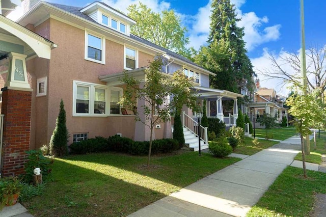 american foursquare style home featuring a front lawn and stucco siding