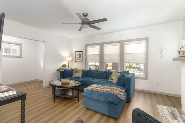 living area featuring light wood-style floors, ceiling fan, and baseboards