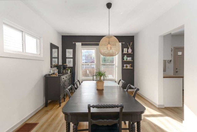 dining space with visible vents, light wood-style flooring, and baseboards