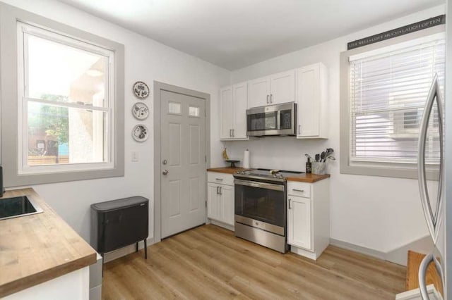 kitchen featuring white cabinets, butcher block counters, and stainless steel appliances