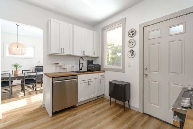 kitchen with stainless steel dishwasher, light wood-style floors, white cabinetry, a sink, and wood counters