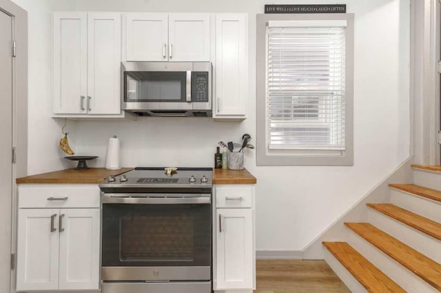 kitchen with stainless steel appliances, wooden counters, and white cabinetry