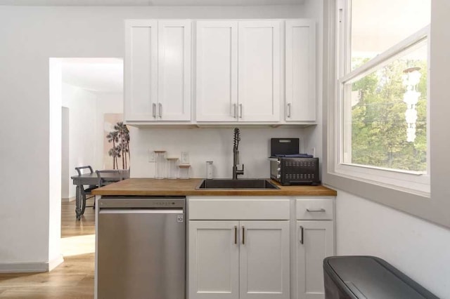 kitchen with butcher block countertops, a wealth of natural light, dishwasher, and a sink