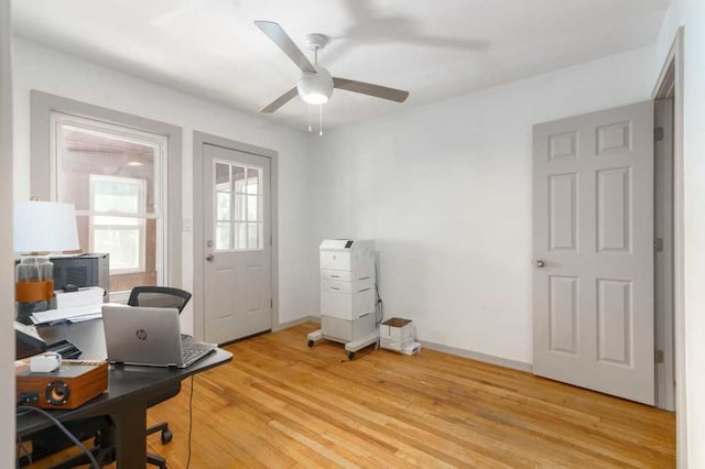 home office with light wood-style floors, ceiling fan, and baseboards