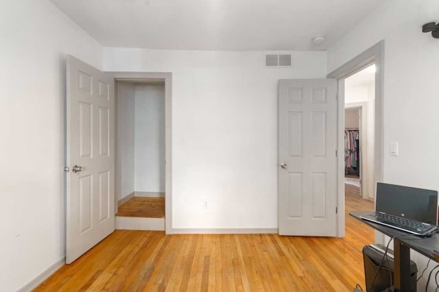 unfurnished bedroom with light wood-style flooring, visible vents, and baseboards