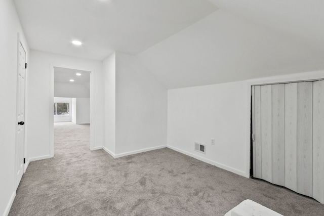 bonus room with lofted ceiling, visible vents, light carpet, and baseboards