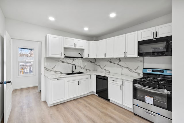 kitchen with light stone countertops, black appliances, white cabinetry, and a sink