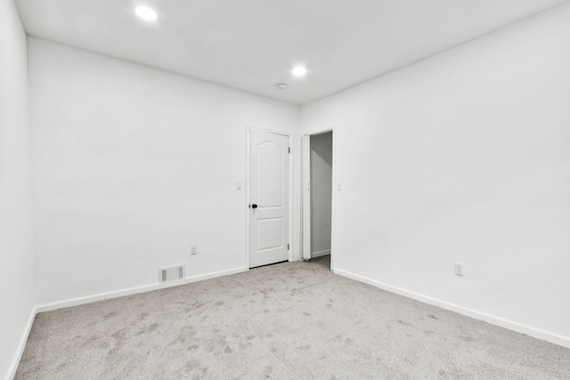 empty room with light colored carpet, visible vents, baseboards, and recessed lighting