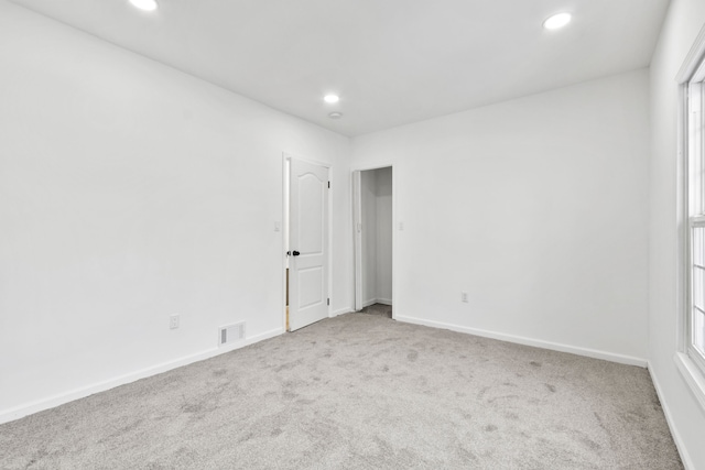 unfurnished room with recessed lighting, baseboards, visible vents, and light colored carpet